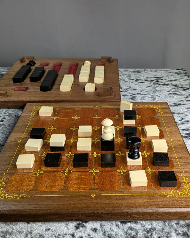 Walnut and mahogany Tak board with gold inlay and cream and black pieces in play